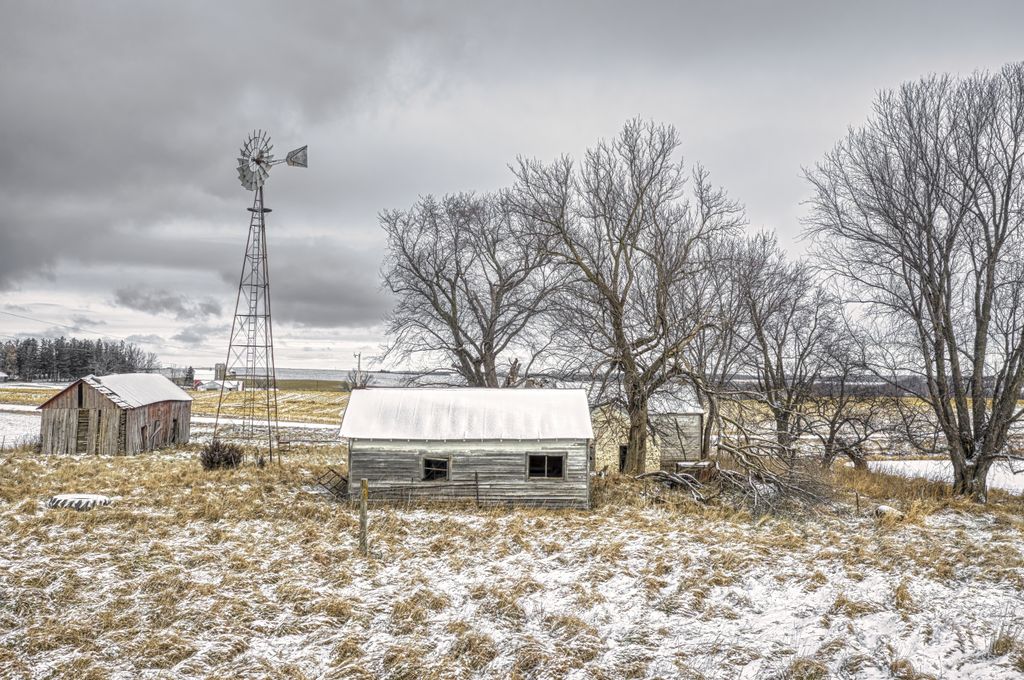 A scenic winter view of a rural farm in Minnesota with snow-covered barns and trees.