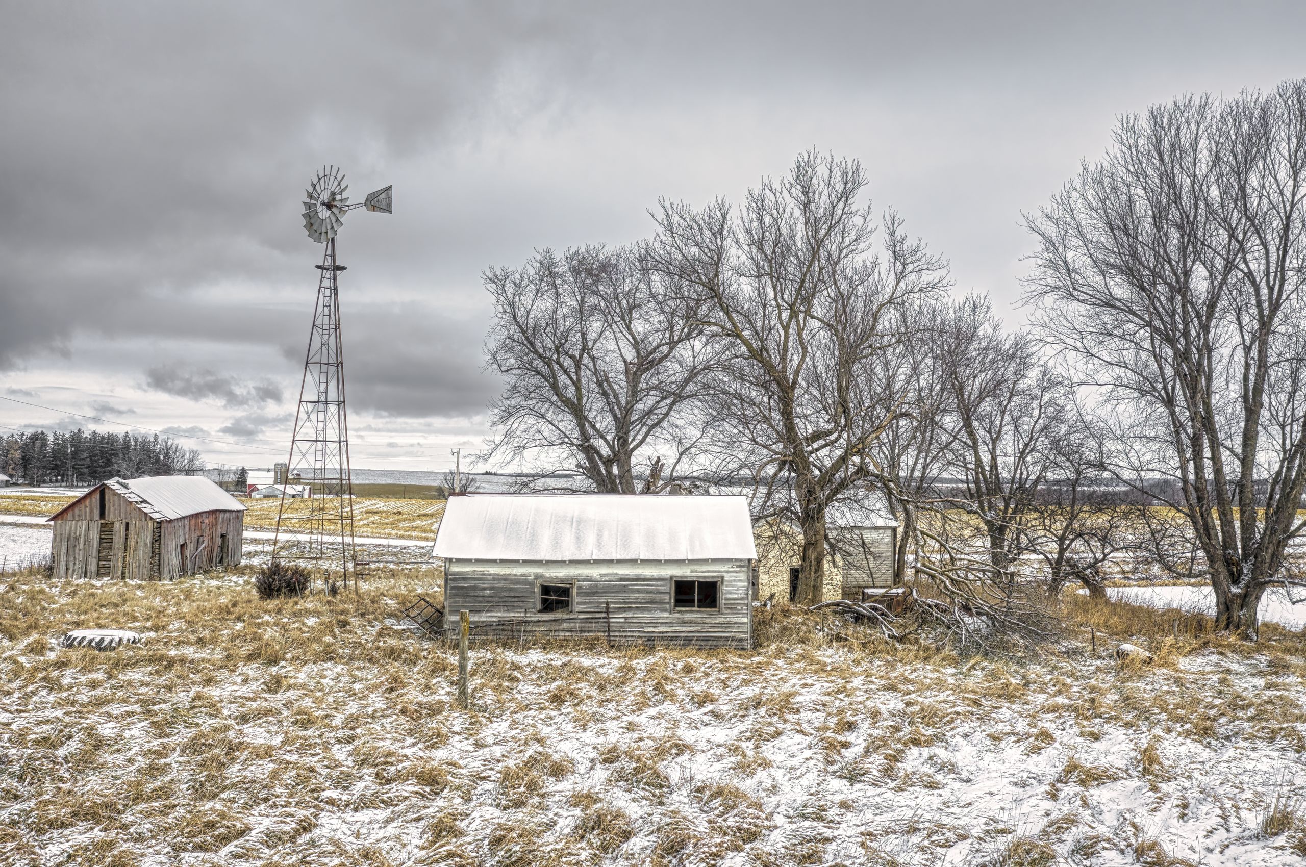 A scenic winter view of a rural farm in Minnesota with snow-covered barns and trees.