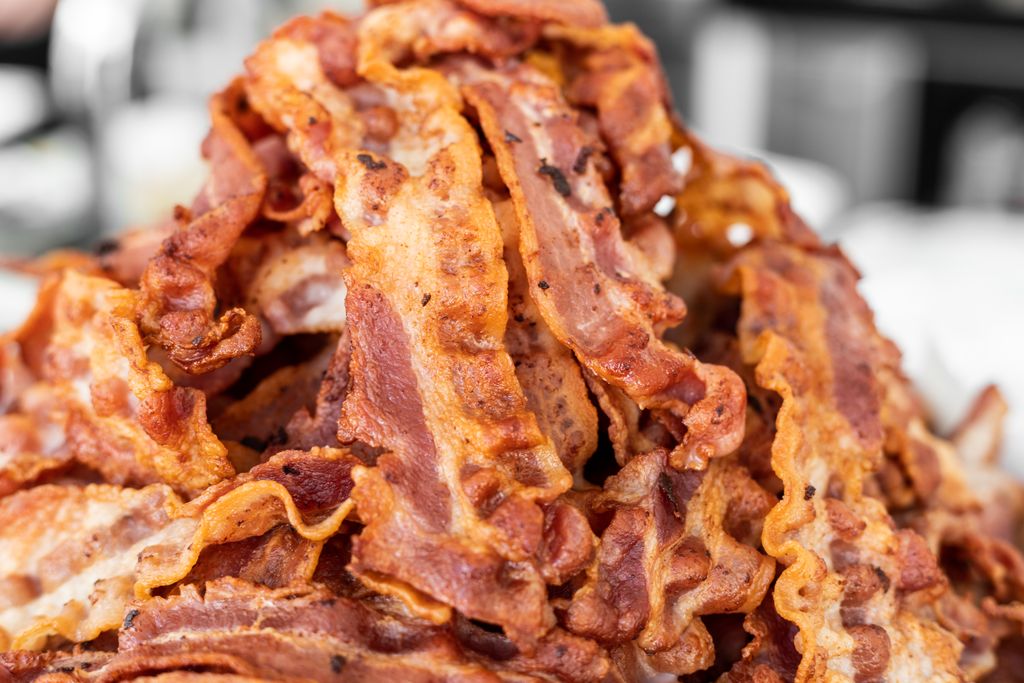 A heap of crispy cooked bacon strips on display, showcasing delicious texture and color.