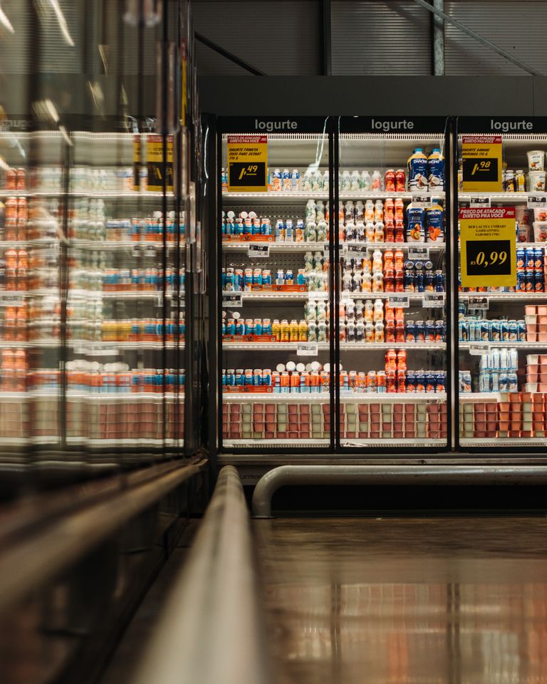 A well-lit supermarket aisle showcasing a variety of yogurt products in a refrigerated display.