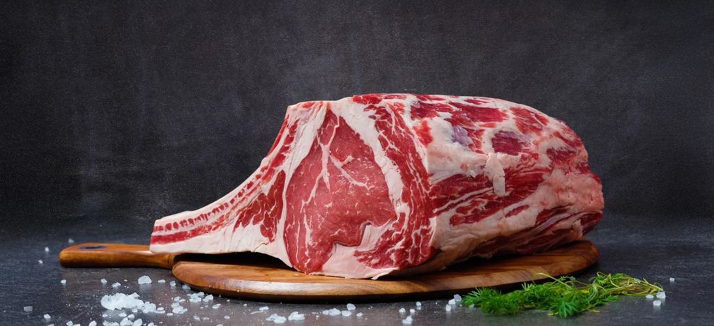 High-quality raw ribeye beef on a wooden board, perfect for gourmet cooking.